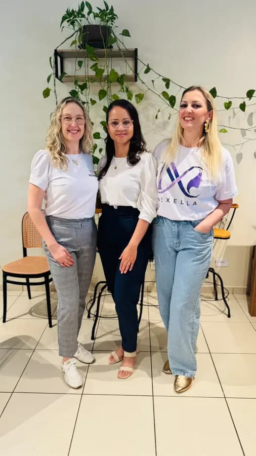 Três participantes sorrindo juntas, uma delas com camiseta da Nexella
